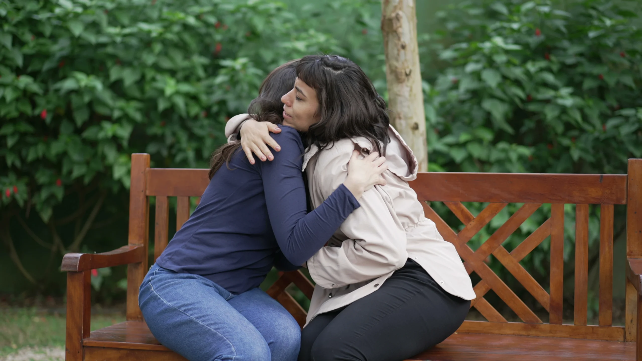 two women comforting each other on a park bench, suffer from greif and loss